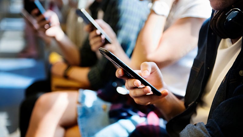 People sitting in a row looking at their smartphones.