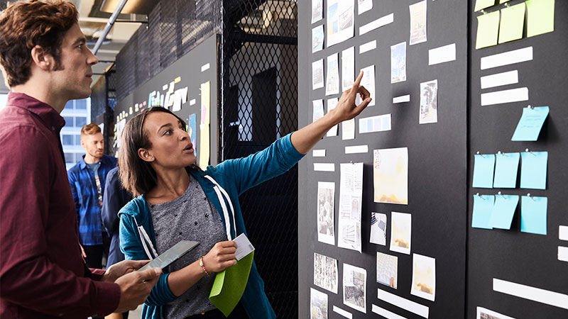 Visa Developer Man and woman discussing an item on a Scrum Task Board.