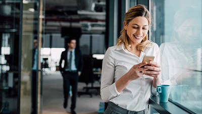 Mujer sonriente utilizando su celular en la oficina